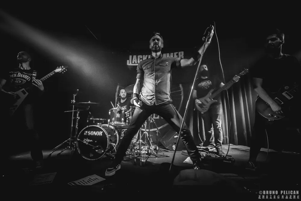 Jackhammer en concert, le chanteur bras levé devant le groupe